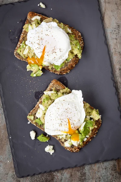Smadrede Avocado og feta toast med pocherede æg - Stock-foto