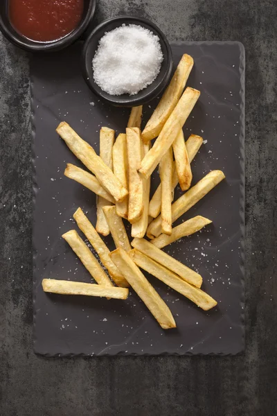 Franse frietjes met zeezout op zwarte leisteen — Stockfoto