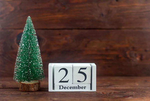 Christmas.December 25 on the calendar.Calendar with a small Christmas tree on a wooden background. Winter. Empty space for text.