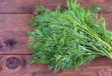 Ahşap bir masanın arka planında bir demet taze dereotu. Ahşap arka planda taze organik dereotu. Kırsal bir tahtaya yakın çekim yap.