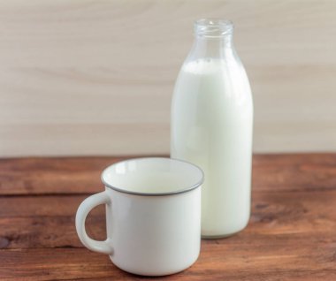 Tahta bir masada bir şişe süt ve bir kupa..