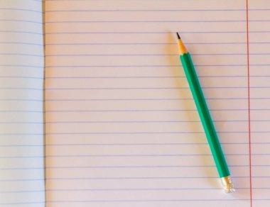 Okula dönüş, eğitim konsepti. Yeşil kalem ve defter yakın plan..