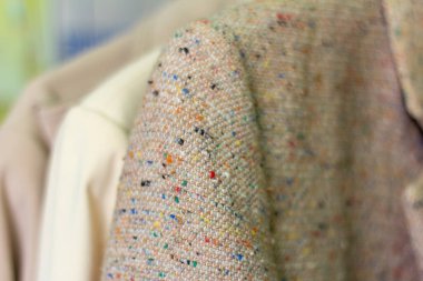 Elbiseleri farklı olan askılara yakın çekim. Kadın ceketleri askıda asılı. Seçici odak, sığ alan derinliği.