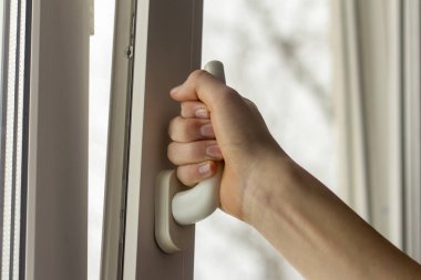 Ergenlerin eli odayı havalandırmak için pencereyi açar..