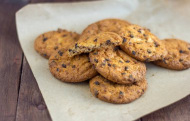 Tahta arka planda çikolata parçalı lezzetli yulaf ezmeli kurabiyeler.