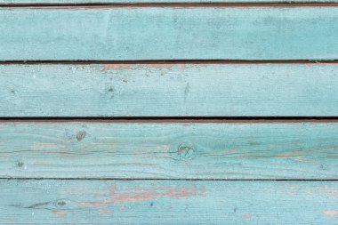 Eski ahşap duvar maviye boyanmış, aşınmış ahşap zemin çivi ve kesiklerle kaplı..