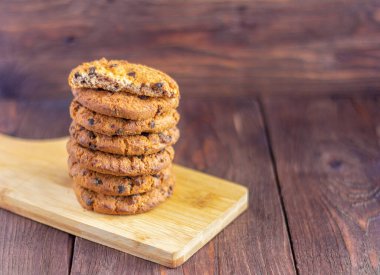 Tahta arka planda çikolata parçalı lezzetli yulaf ezmeli kurabiyeler.