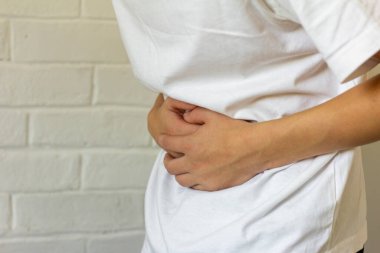 Genç adam elleriyle karnını tutuyor, acı ve kasılmalar yaşıyor..