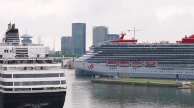 Amsterdam, Hollanda, 9 Mart 2024 - Virgin yolcu gemisi durağan Vasco da Gama gemisinin yanından geçerek turizm, seyahat endüstrisi, şehir limanı