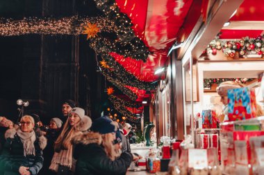 Köln, Almanya, 10 Aralık 2022 - Noel pazarının tadını çıkaran ziyaretçiler, Noel ışıklarıyla süslenmiş tezgahlar, akşam saatleri