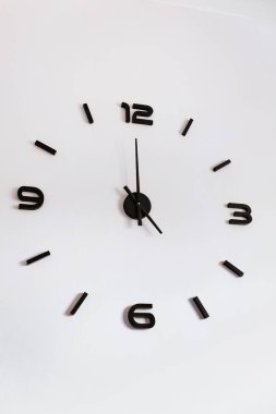 Temiz minimalist düzenine sahip çağdaş siyah duvar saati tam olarak beyaz bir iç duvar, ev dekorasyonu, zaman kavramı üzerinde zamanı gösterir