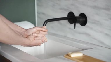 Musluk suyunun altında sabunla ovalanan ve iyice yıkanan elleri yakından görmek mermer bir lavaboda, modern banyo içinde, sağlık hizmetlerinde, hijyende
