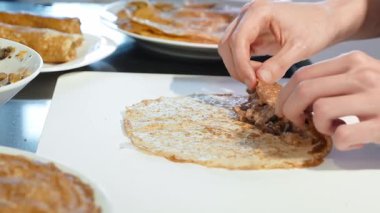 Aşçı, krep kenarını mantar karışımının üzerine katlar ve tabağı kaplamadan önce şekiller yuvarlanır. Doldurulmuş leziz krep paketleme işlemi.