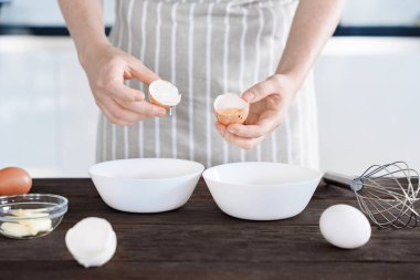 Eller taze yumurta kırar ve yumurta sarısını beyaz yumurtadan ayırır ahşap masa üzerinde hamuru veya hamuru kek için hazırlar, ev yemeği, pişirme süreci