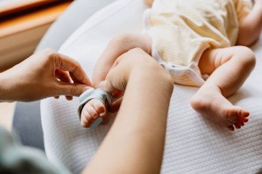 Ebeveynler bebek ayaklarına giyilebilen sağlık monitörü takarken, bebek evde paspasın değişmesi, ÖYD önleme, bebek izleme
