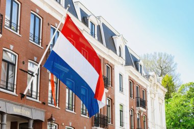 Amsterdam, Hollanda - 26 Nisan 2025: Hollanda bayrağı güneşli bir günde Hollanda 'da bina cephesi, ulusal sembol, vatanseverlik, mimarlık, kentsel çevre.
