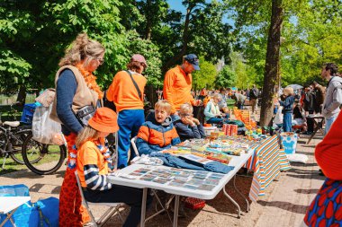 Amsterdam, Hollanda - 26 Nisan 2025: Hollanda 'da Koningsdag sırasında açık hava bit pazarında ürün satan aileler ve çocuklar, serbest piyasa ticareti, festival topluluğu etkinliği.