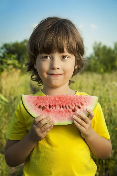 Šťastné dítě jíst meloun v zahradě — Stock fotografie