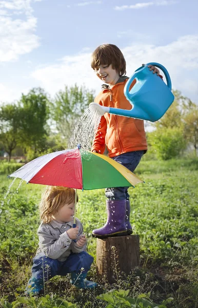 Два счастливых брата с зонтиком на открытом воздухе — стоковое фото