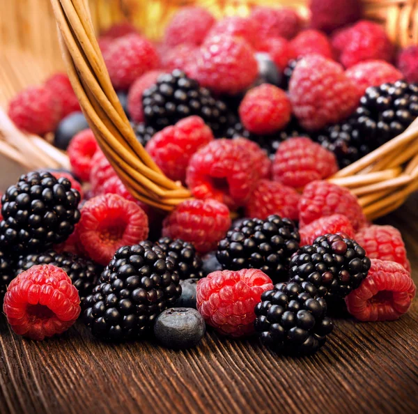 Verschiedene Beeren in einem Korb auf einem Holztisch — Stockfoto