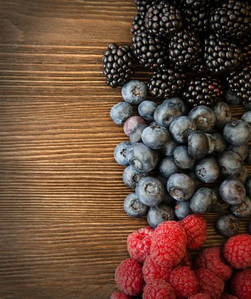 Framboises et mûres éparpillées sur la table en bois — Photo