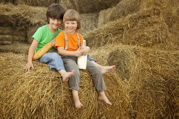 Boys on a haystack with bread and milk — Stock Photo, Image