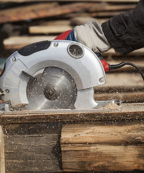 Een mens werken buiten met een cirkelzaag — Stockfoto