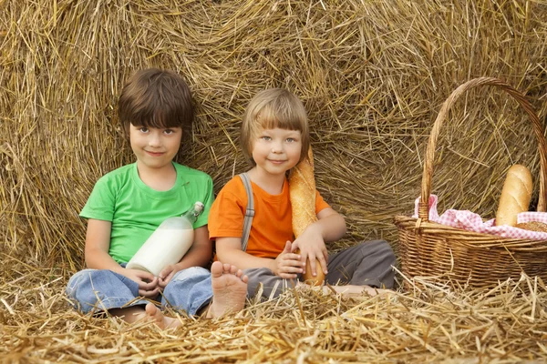 Jongens op een hooiberg met brood en melk — Stockfoto