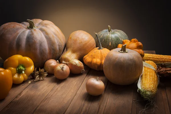 Őszi tökök és más gyümölcsök és zöldségek egy fából készült asztal — Stock Fotó