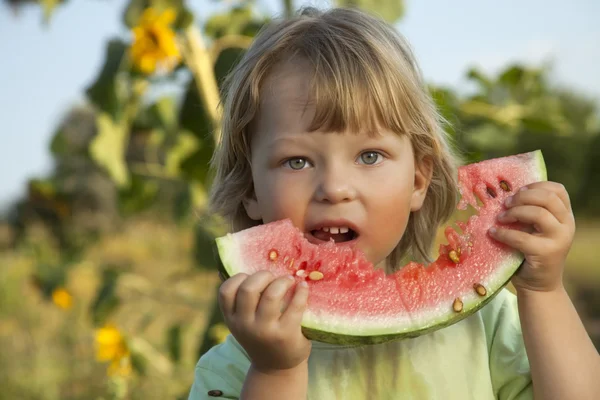 Glückliches Kind isst Wassermelone im Garten — Stockfoto