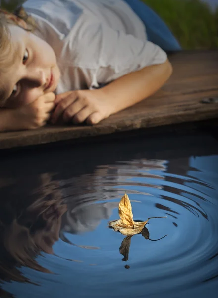 Jongen spelen met blad schip in water (focus op schip) — Stockfoto