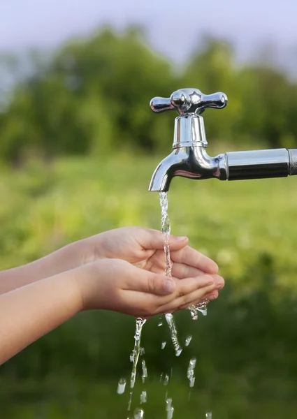 Pojke tvättar sin hand under kranen i trädgården — Stockfoto