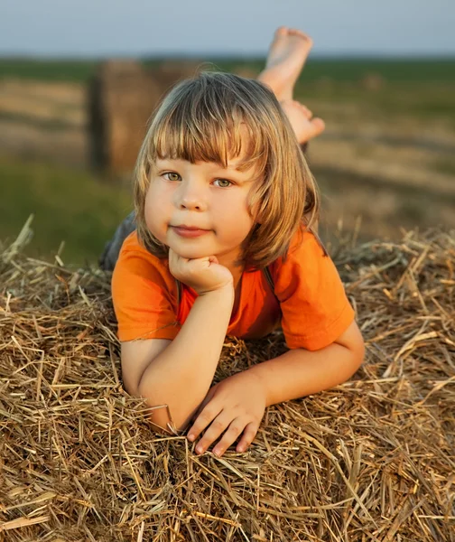 Menino em um palheiro no campo — Fotografia de Stock