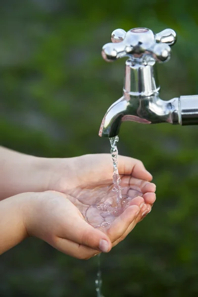 Pojke tvättar sin hand under kranen i trädgården — Stockfoto