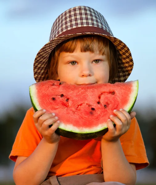 Glückliches Kind isst Wassermelone im Garten — Stockfoto
