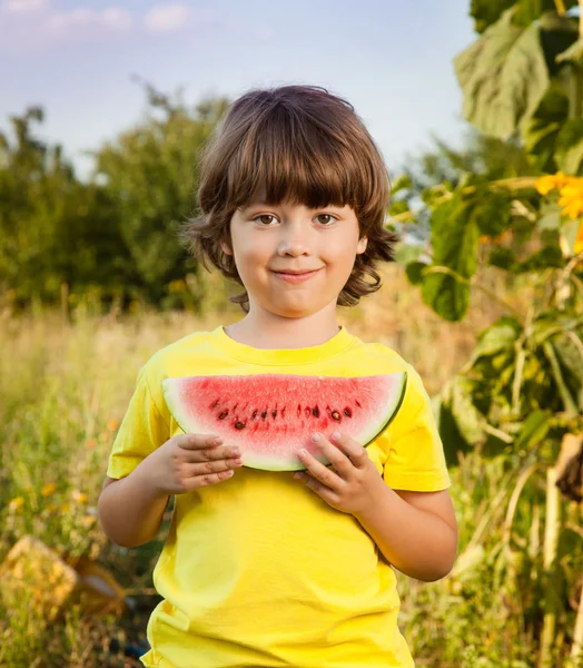 Lyckligt barn äta vattenmelon i trädgården — Stockfoto