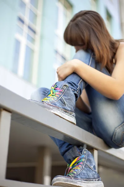 Sad lonely girl meditates sitting on the railing of city (focus — Stock Photo, Image