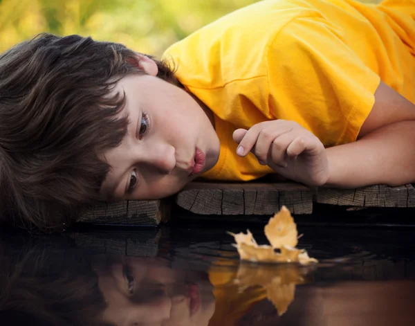 Ragazzo giocare con foglia nave in acqua — Foto Stock