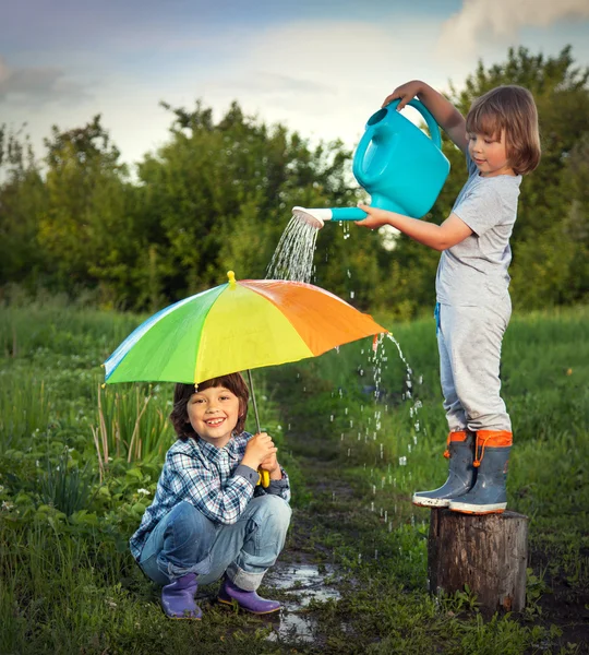 Dos hermanos juegan bajo la lluvia al aire libre —  Fotos de Stock