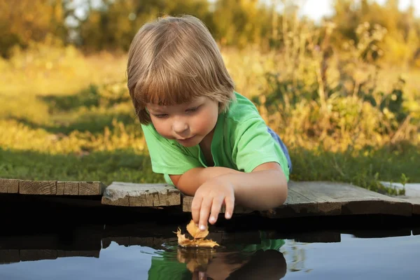 Niño jugar con hoja barco en agua —  Fotos de Stock