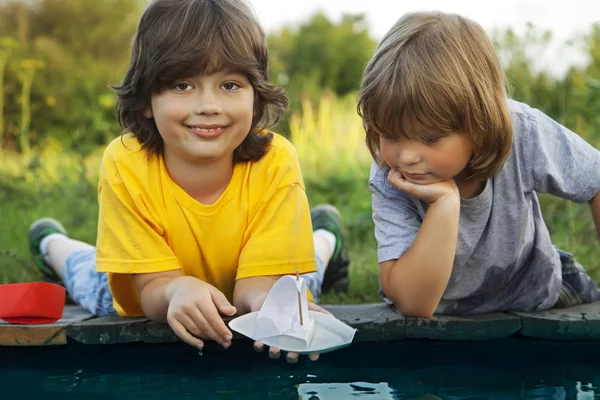 Due ragazzi hanno permesso barche di carta dal molo del fiume — Foto Stock