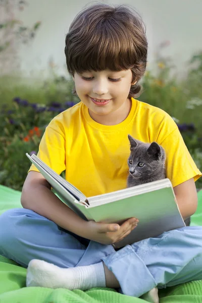 庭で子猫と本、ペットを読む子を読んでいる少年 — ストック写真