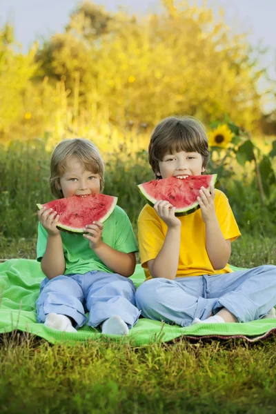 Criança feliz comendo melancia no jardim — Fotografia de Stock