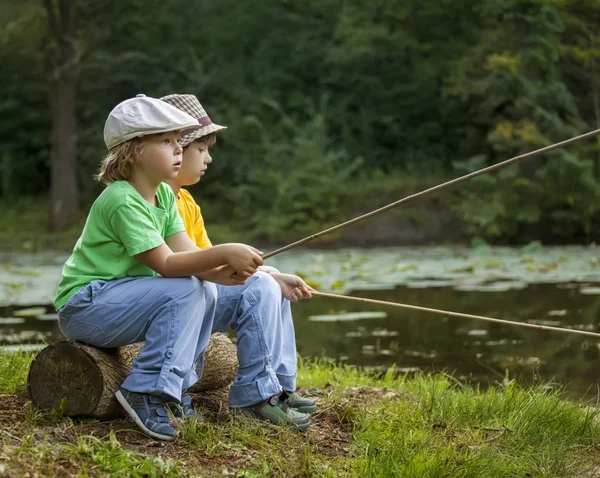 Glada pojkar fiska på floden, två barn av fisherma — Stockfoto