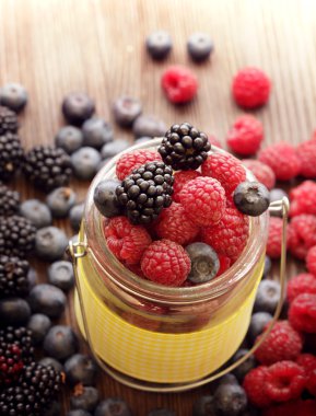 ahşap bir masa üzerinde bir sepet içinde farklı meyveler