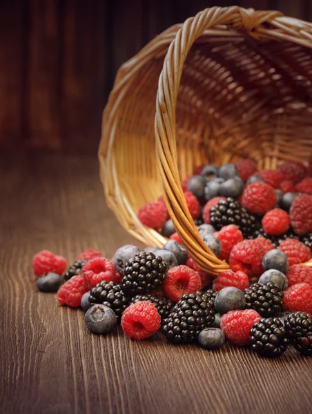 Verschiedene Beeren in einem Korb auf einem Holztisch — Stockfoto