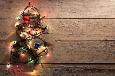 Mavi ahşap arka planda ışıklandırılmış Noel ağacı, karton süsleme. Ev yapımı