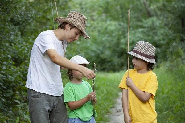 快乐的男孩去河边钓鱼 渔夫的三个孩子带着钓竿在湖边钓鱼 — 图库照片
