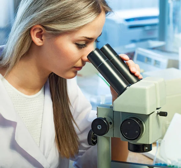 beauty scientist Looks in a microscope in chemical laboratory