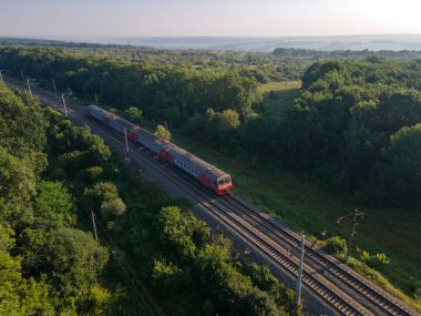 Yaz ormanında tren ve demiryolu sisli gündoğumunda. Kırsal demiryolu manzaralı. Hava görünümü